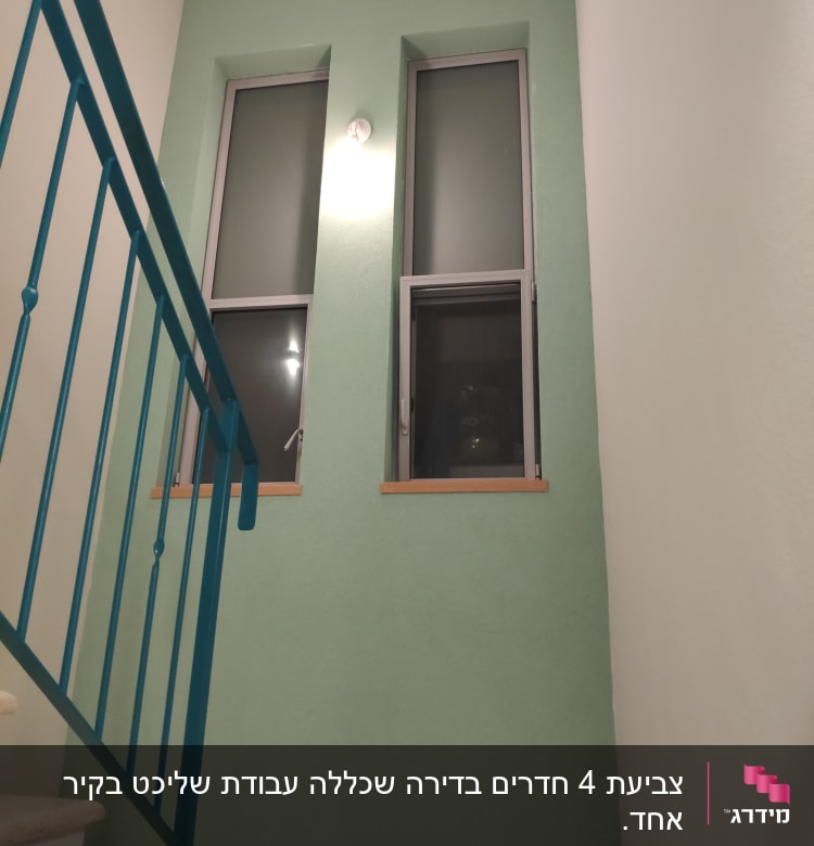 קיר צבוע בירוק עם חלונות ומעקה כחול